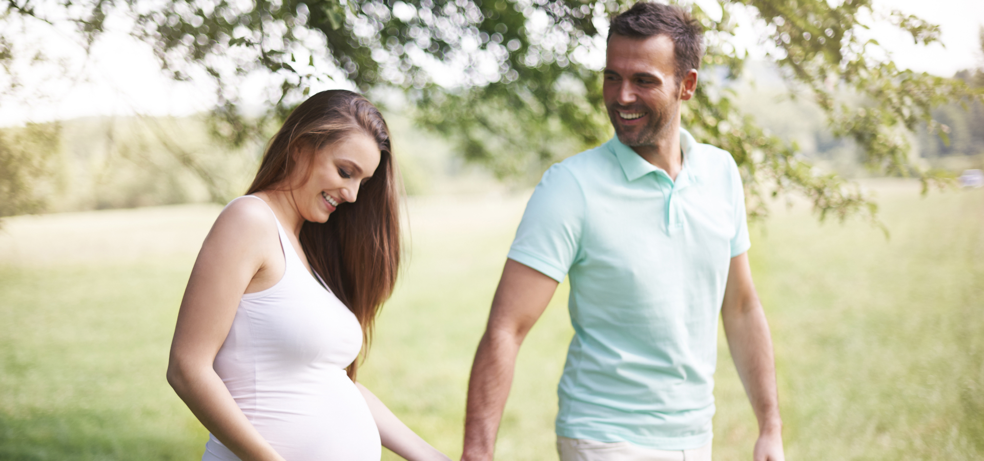 Happy pregnant couple walking in the nature