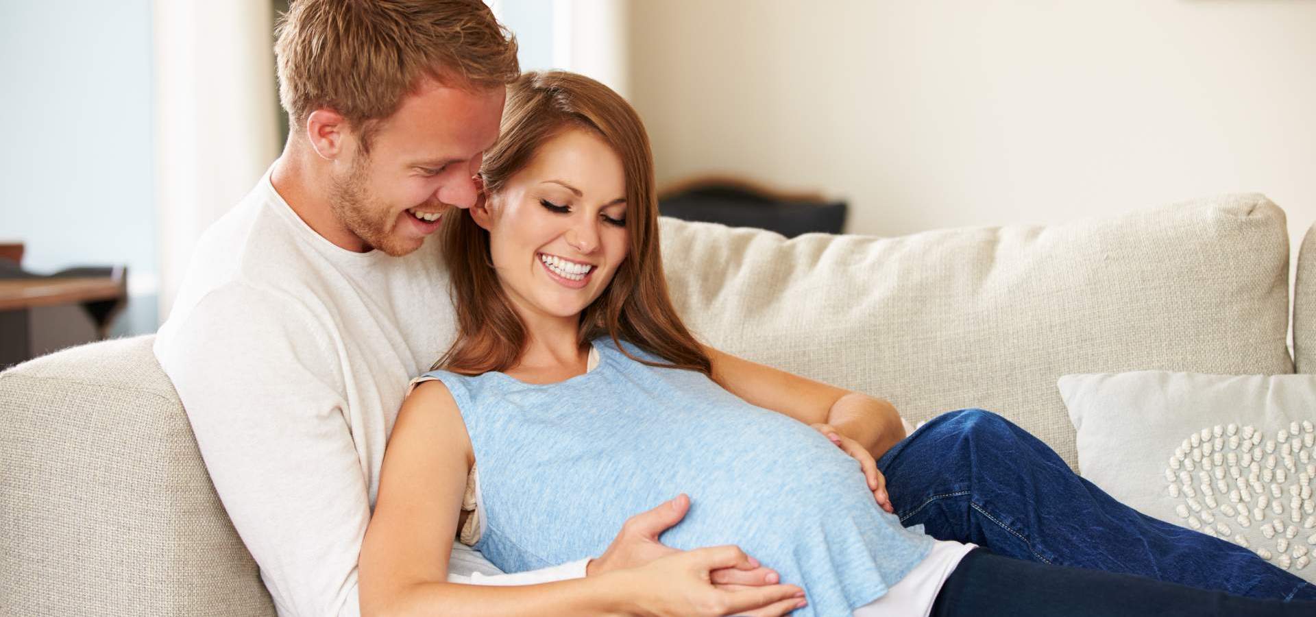 Happy couple placing their hands on a pregnant belly
