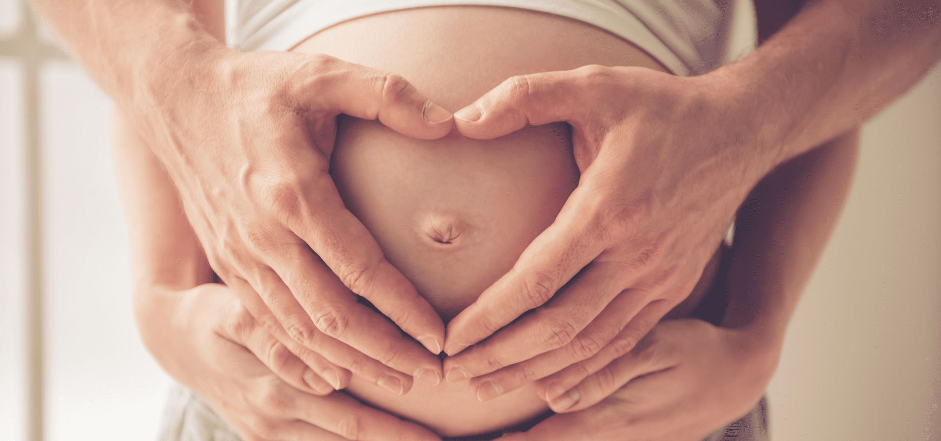Male and female hands carefully holding a pregnant belly