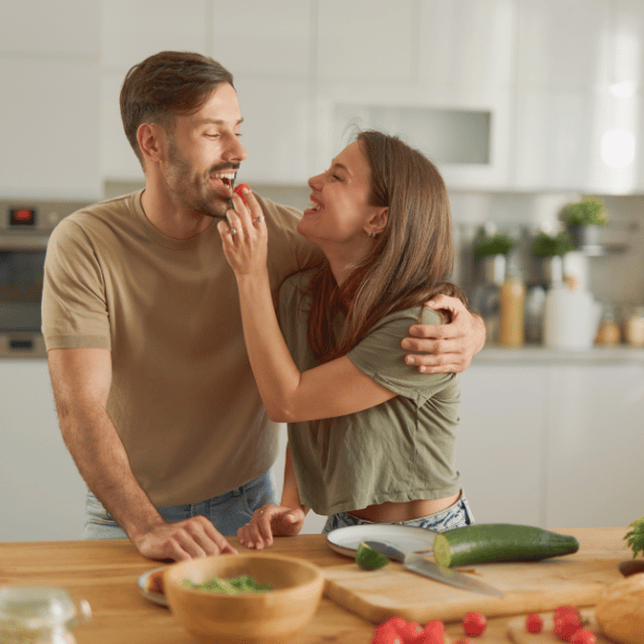 Happy couple preparing healthy meals at home to support fertility, preconception health and their journey to parenthood